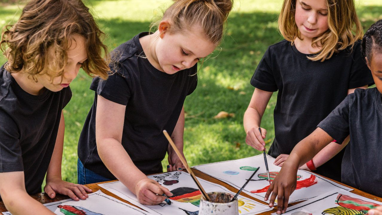 Children participating in social emotional learning for kids through art, painting together outdoors to support emotional development