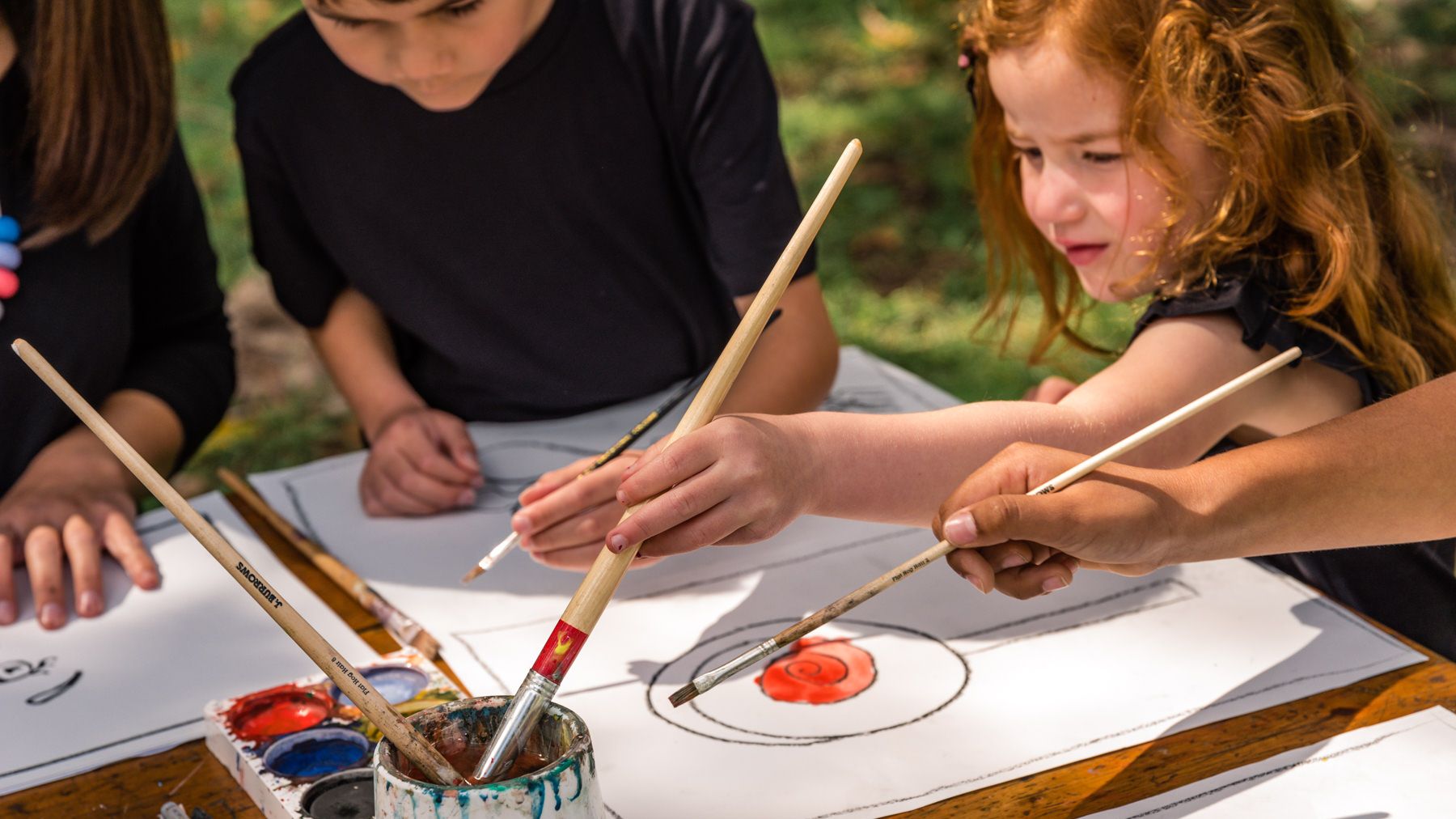 Children enjoying a mindful art activity outdoors as part of emotional wellbeing activities for kids.