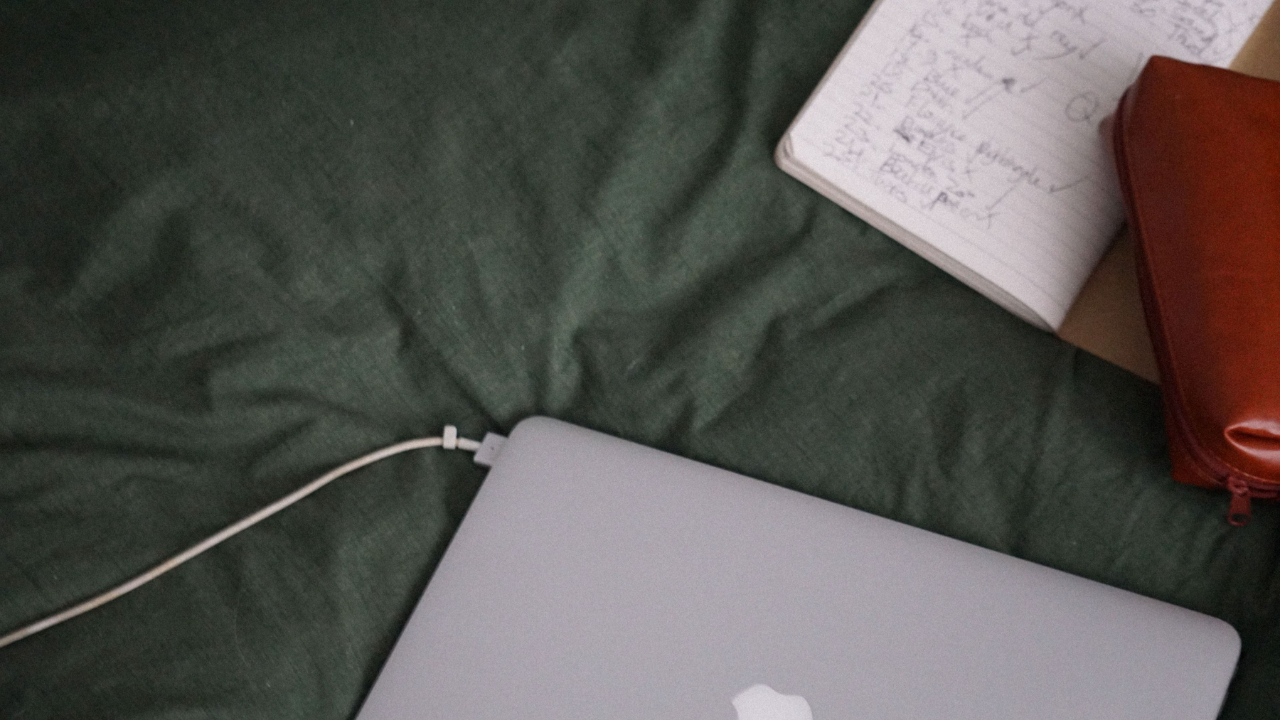 Laptop and notebook on green fabric workspace setup