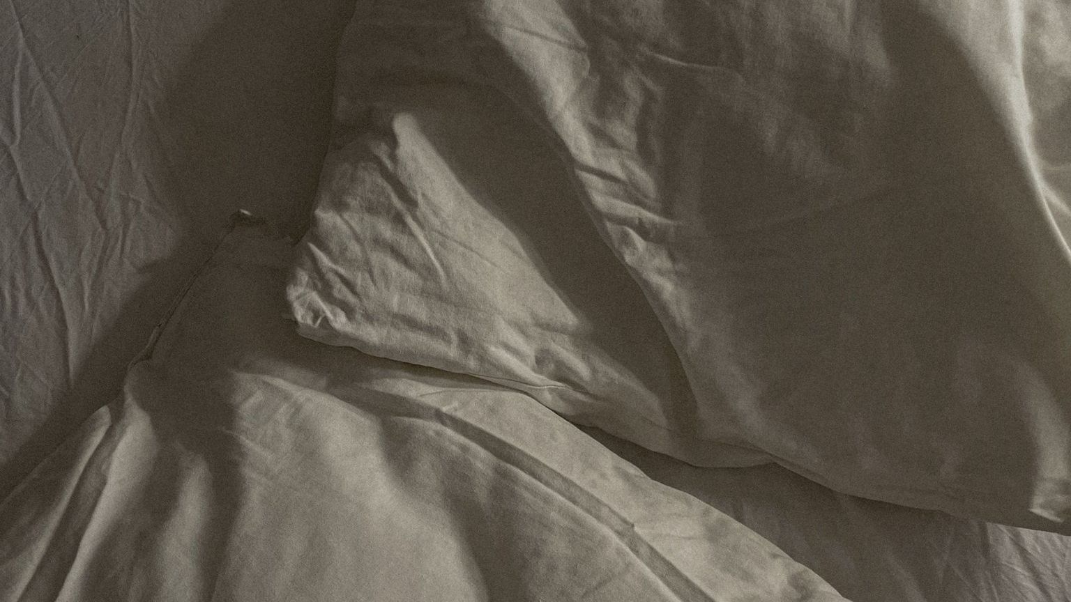 Rumpled white bedding and pillows on unmade bed