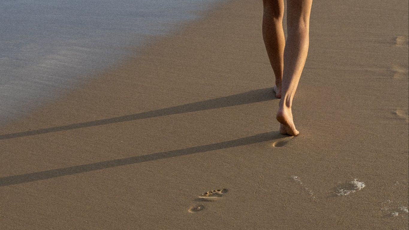Barefoot footprints in wet sand at sunset beach