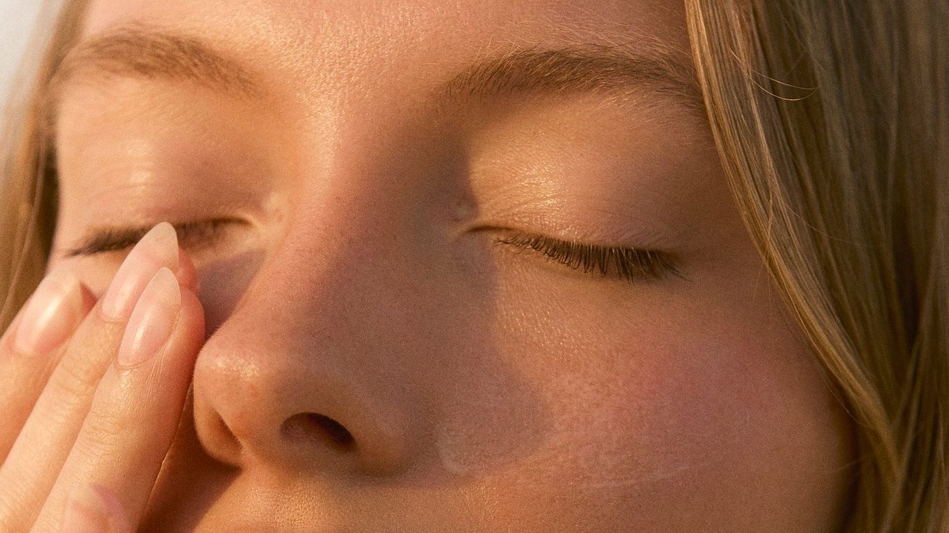 Woman with closed eyes touching her face peacefully