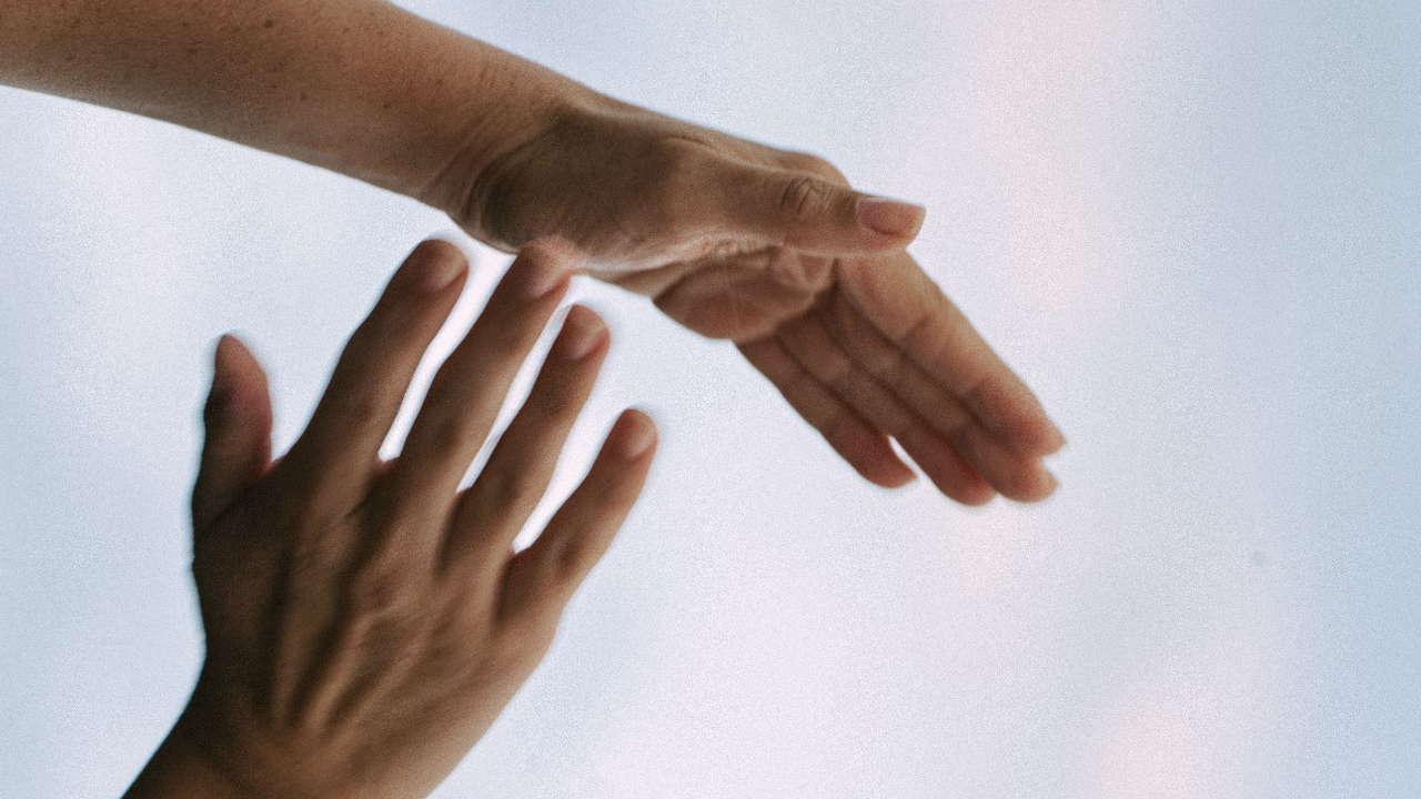 Two hands gesturing together against bright sky backdrop