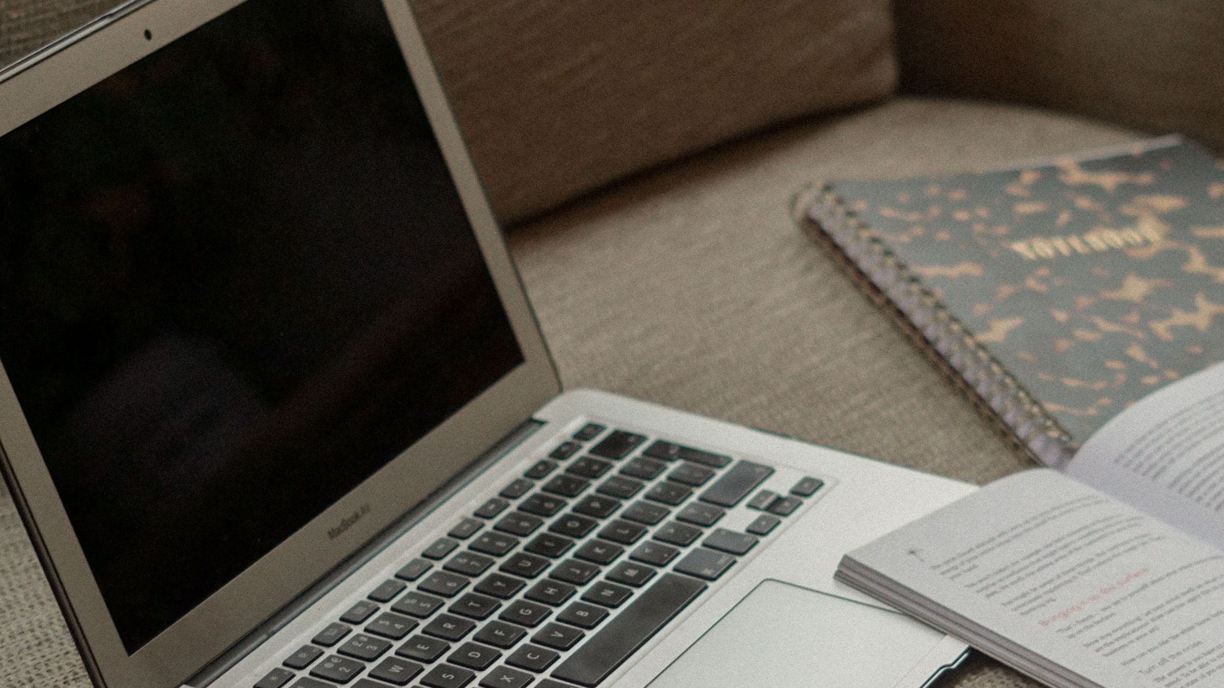 Laptop and notebooks arranged on neutral linen couch