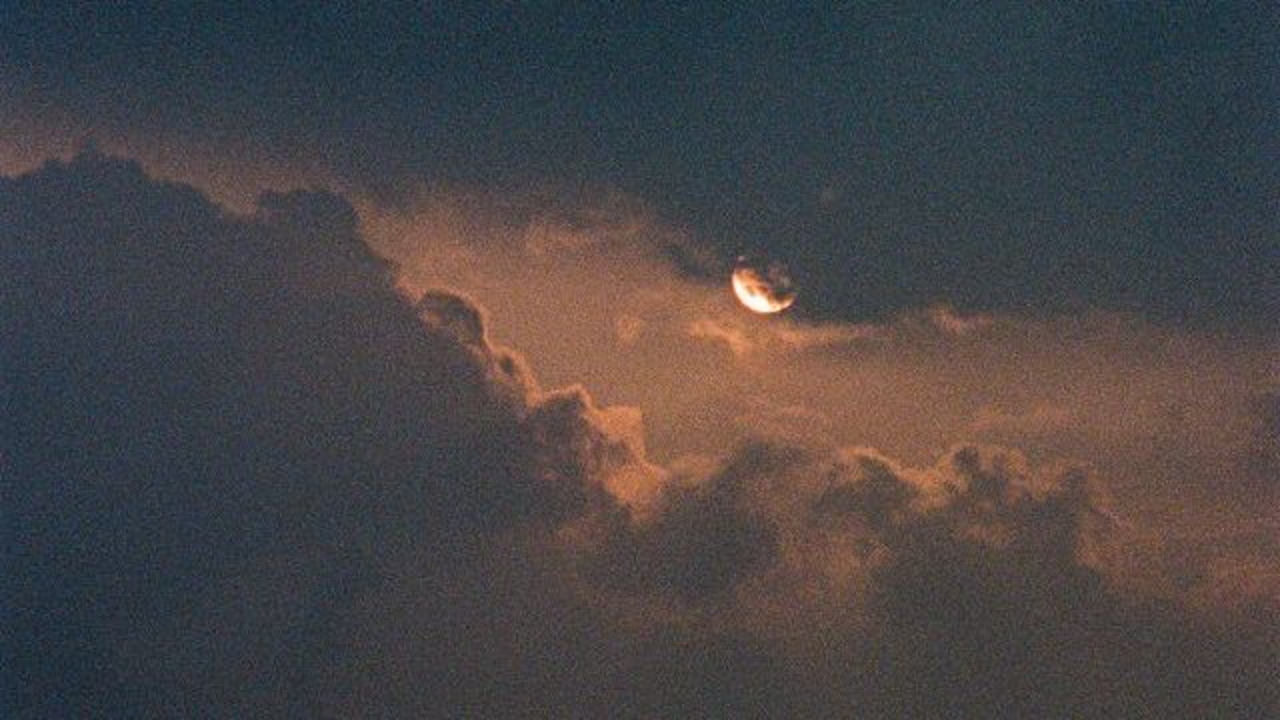 Crescent moon illuminates dramatic storm clouds at dusk