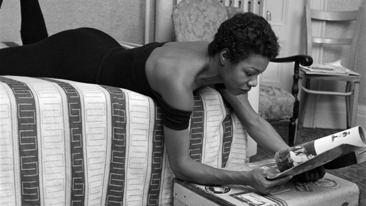Maya Angelou reading a magazine in bed