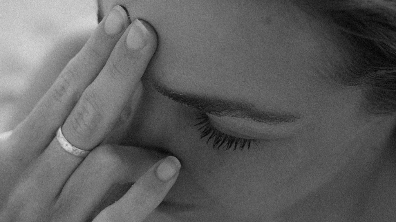 Woman with closed eyes touching face in contemplative moment