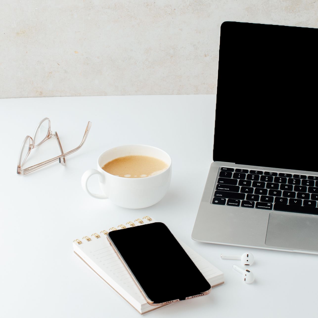 Workspace with a laptop, coffee, phone, and notepad, symbolizing productivity and alignment in business strategy.