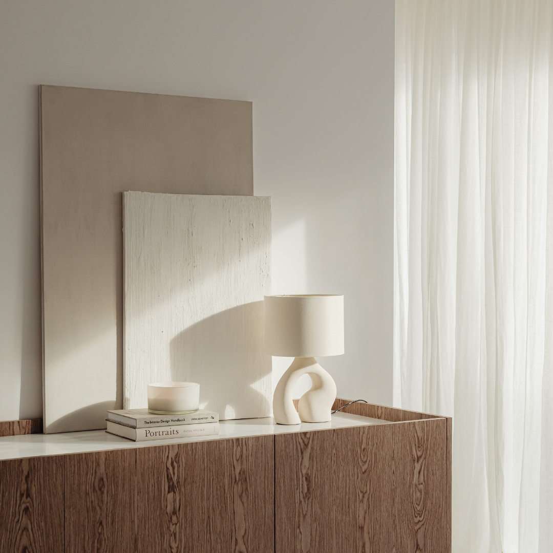 Stylish and modern interior design setup with abstract art, a unique lamp, and natural light, creating a serene atmosphere.