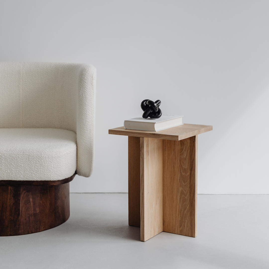 Minimalist wooden side table next to a modern chair, representing thoughtful design and simplicity in home decor.