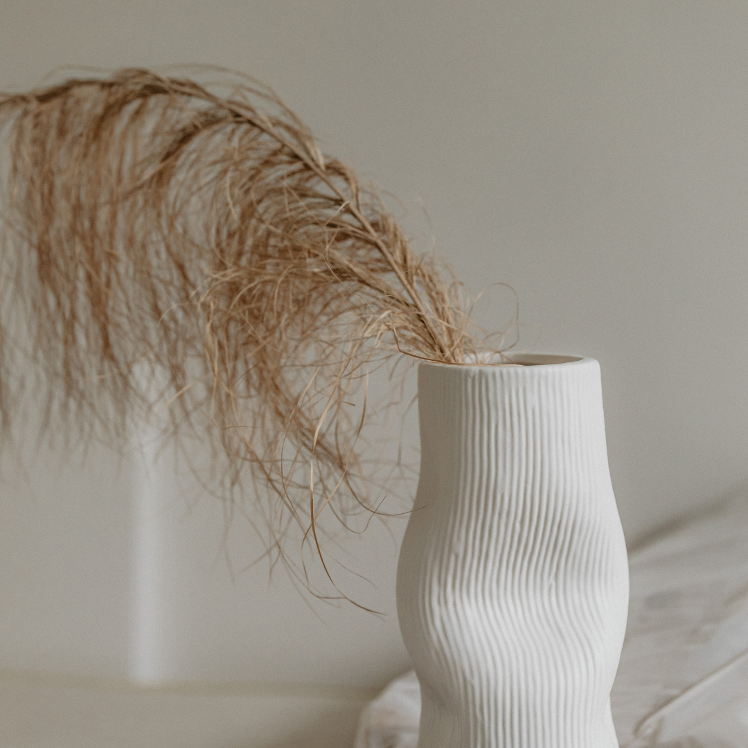 Minimalist white vase with natural dried grass, representing simplicity and elegance in design.