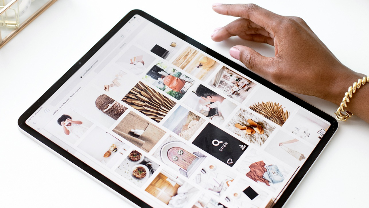 Hand resting on a tablet showing a grid of lifestyle images.