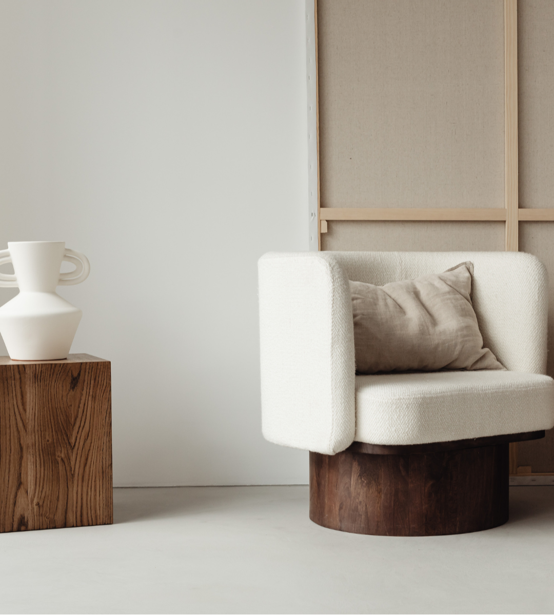 Cozy, modern chair with a wooden side table and decorative vase, representing a blend of comfort and intentional design.