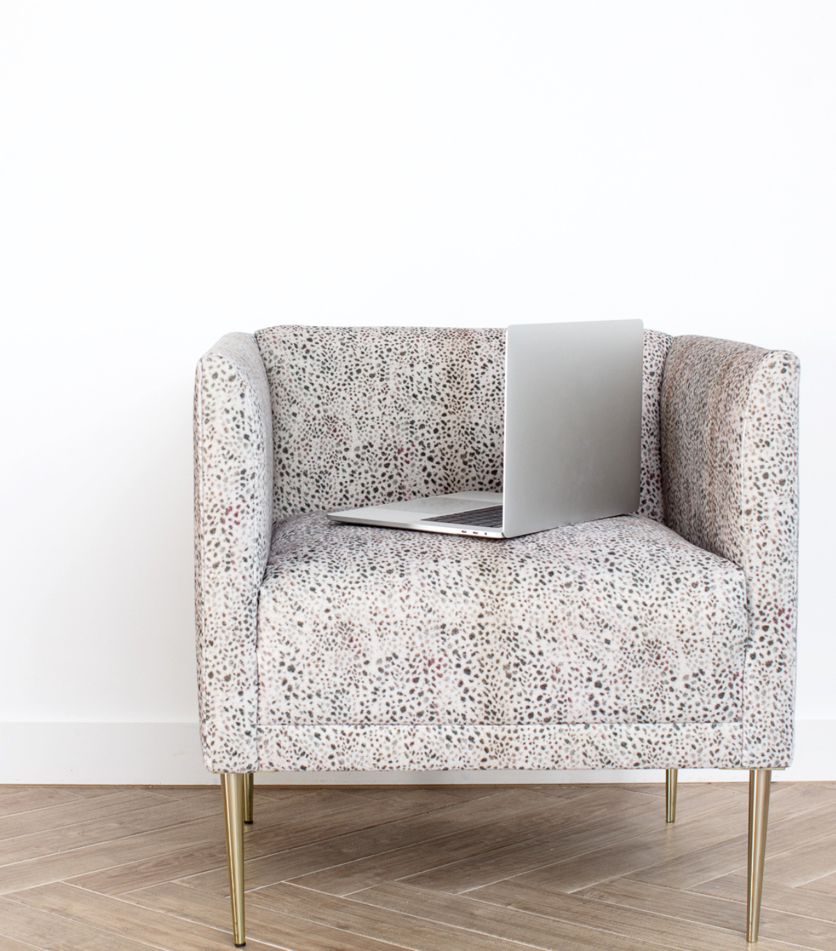 Stylish patterned chair with a laptop, symbolizing the blend of design and productivity in transforming home and business spaces.