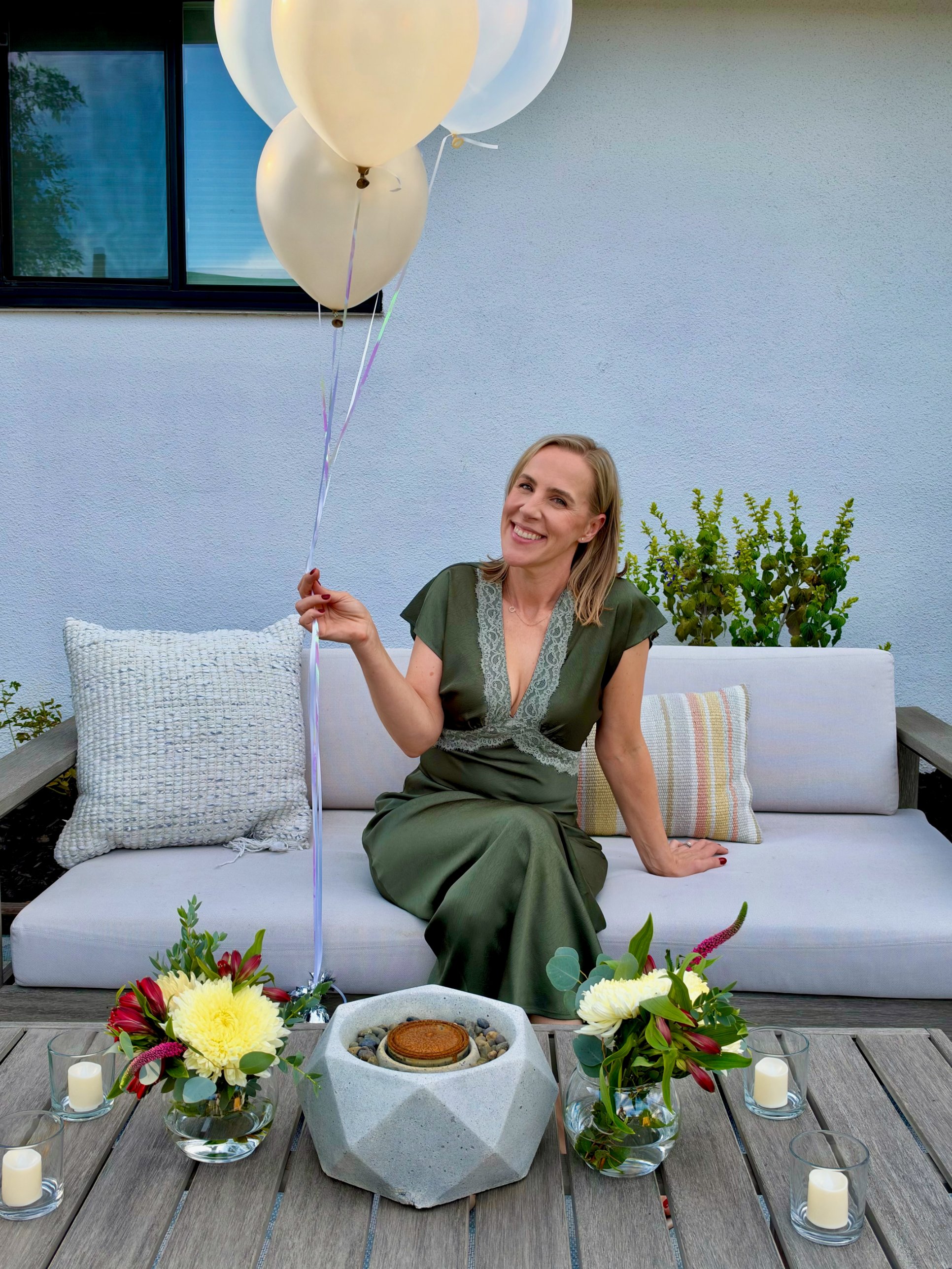 Whitney holding cream balloons on a garden sofa