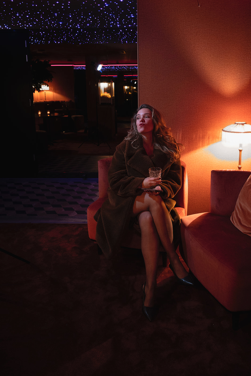 Joyce in een fauteuil in een warm verlichte bar