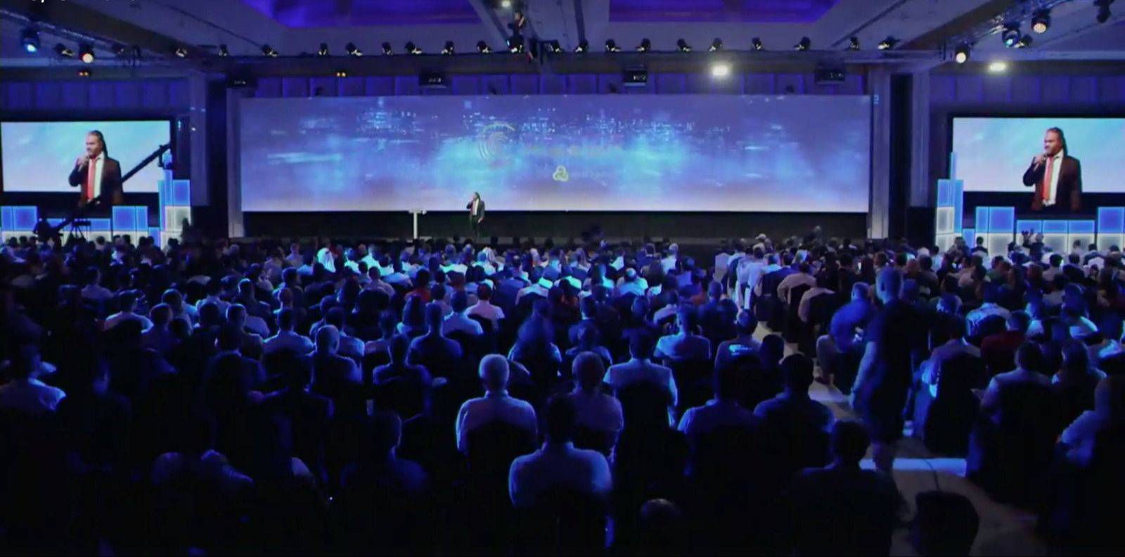 Dave Crane delivering a keynote from a large conference stage to hundreds of attendees.