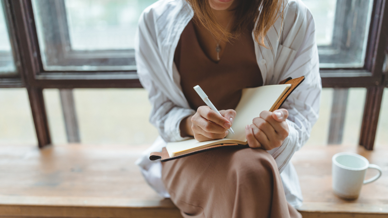 close-up of woman writing in a journal