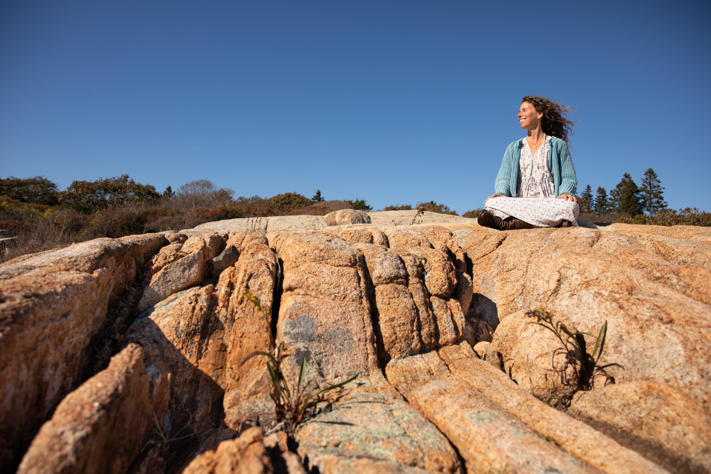 Natalia Rosenbaum seated on rocks in Gloucester under open sky