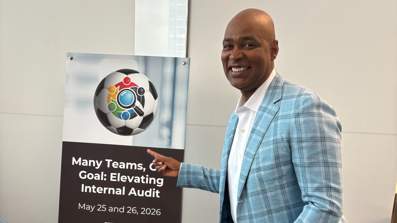 Ivan pointing to a sign that has a FIFA World Cup soccer ball and the words, "Many Teams, One Goal"