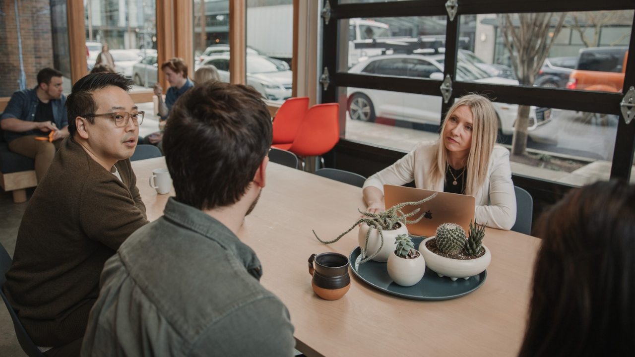 3 people sitting down at a table discussing