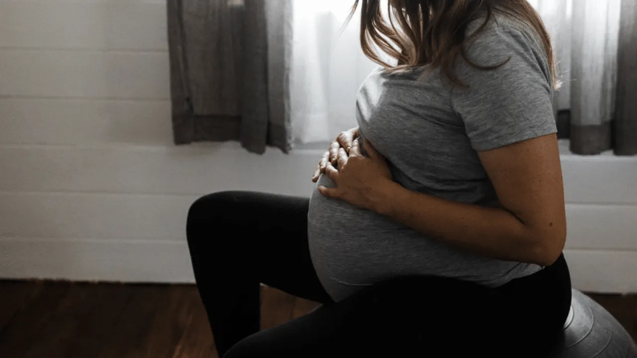 Pregnant mother on birth ball holding belly
