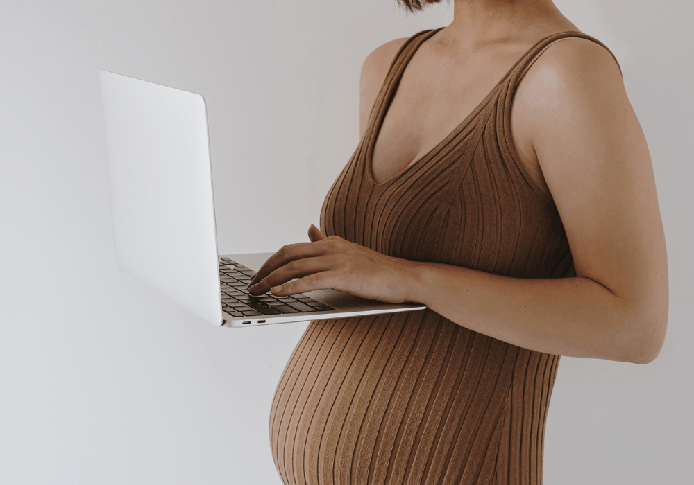 Pregnant mother standing with laptop
