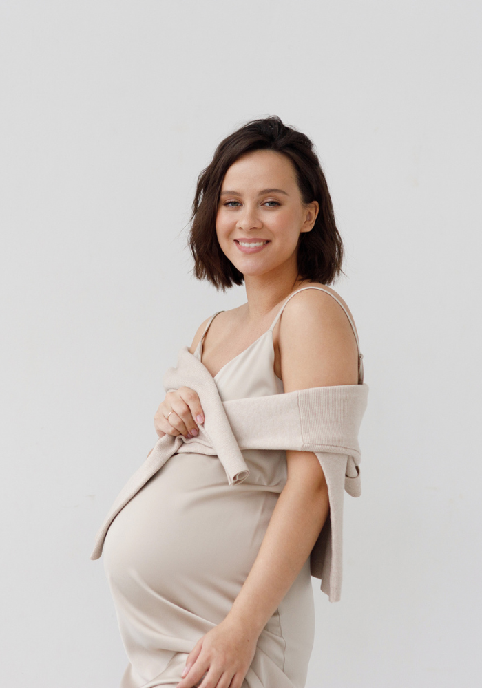A young pregnant girl against a white wall