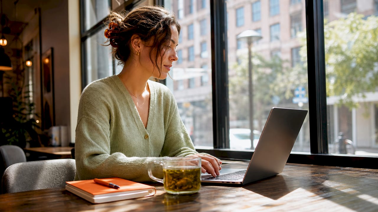 woman coach working on her website at her computer in a bright cafe