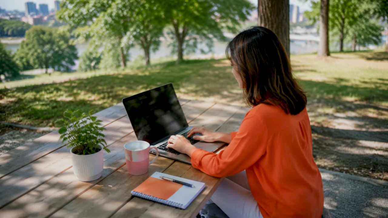 Kajabi Ecosystem Benefits for Coaches: 2026 Guide woman in orange shirt on park bench laptop
