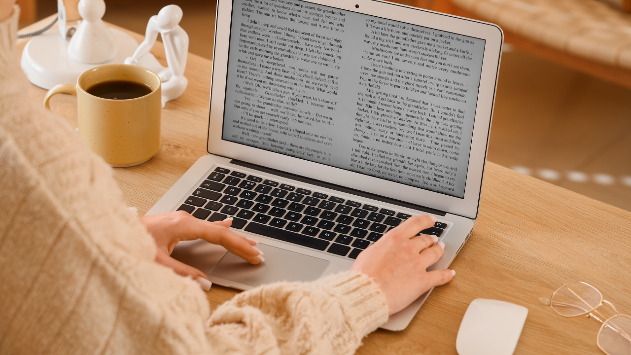 A person in their cozy sweater typing their manuscript on their laptop