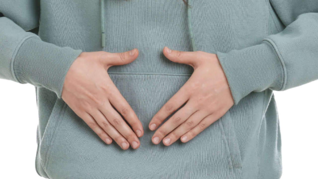 A woman with her hands in a triangle shape on her belly.