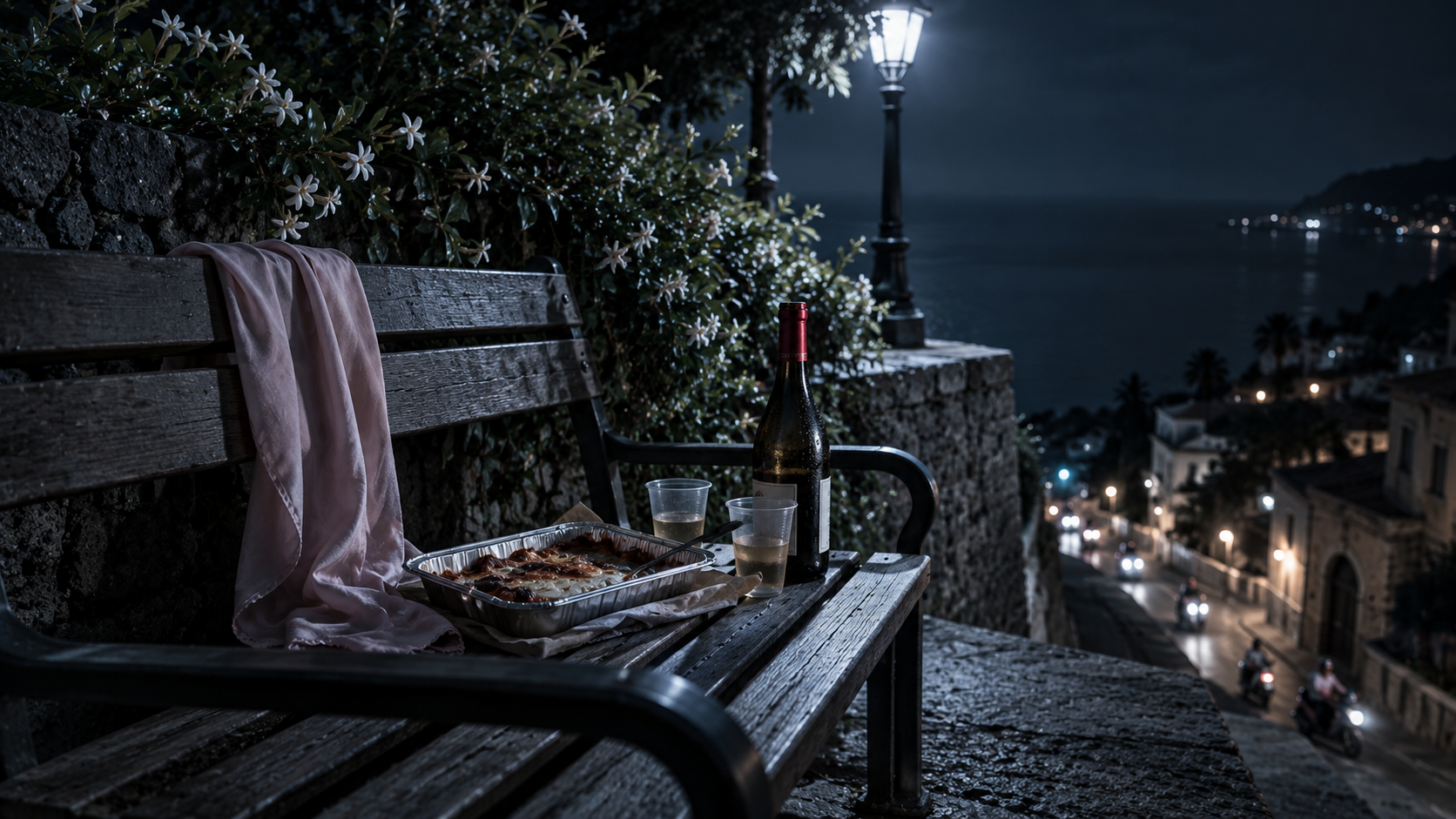 Panchina di un belvedere di sera: teglia di parmigiana, due bicchieri di plastica e una bottiglia, gelsomino sul muretto; sciarpa di seta rosa sulla spalliera.