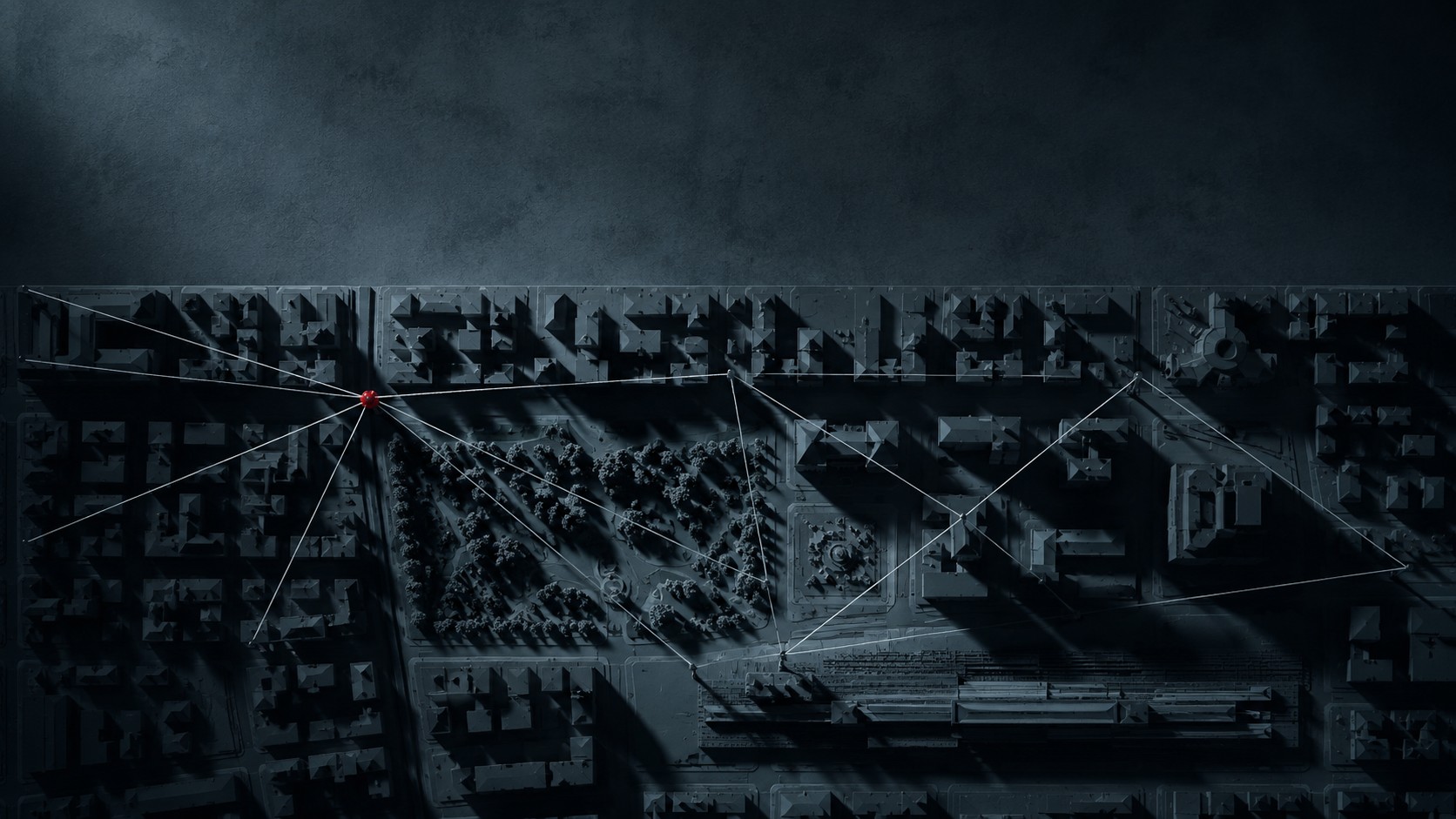 Modello a rilievo di un quartiere visto dall'alto di notte, con fili tesi tra i luoghi a tracciare i percorsi; dove si incrociano, un solo nodo di filo rosso.