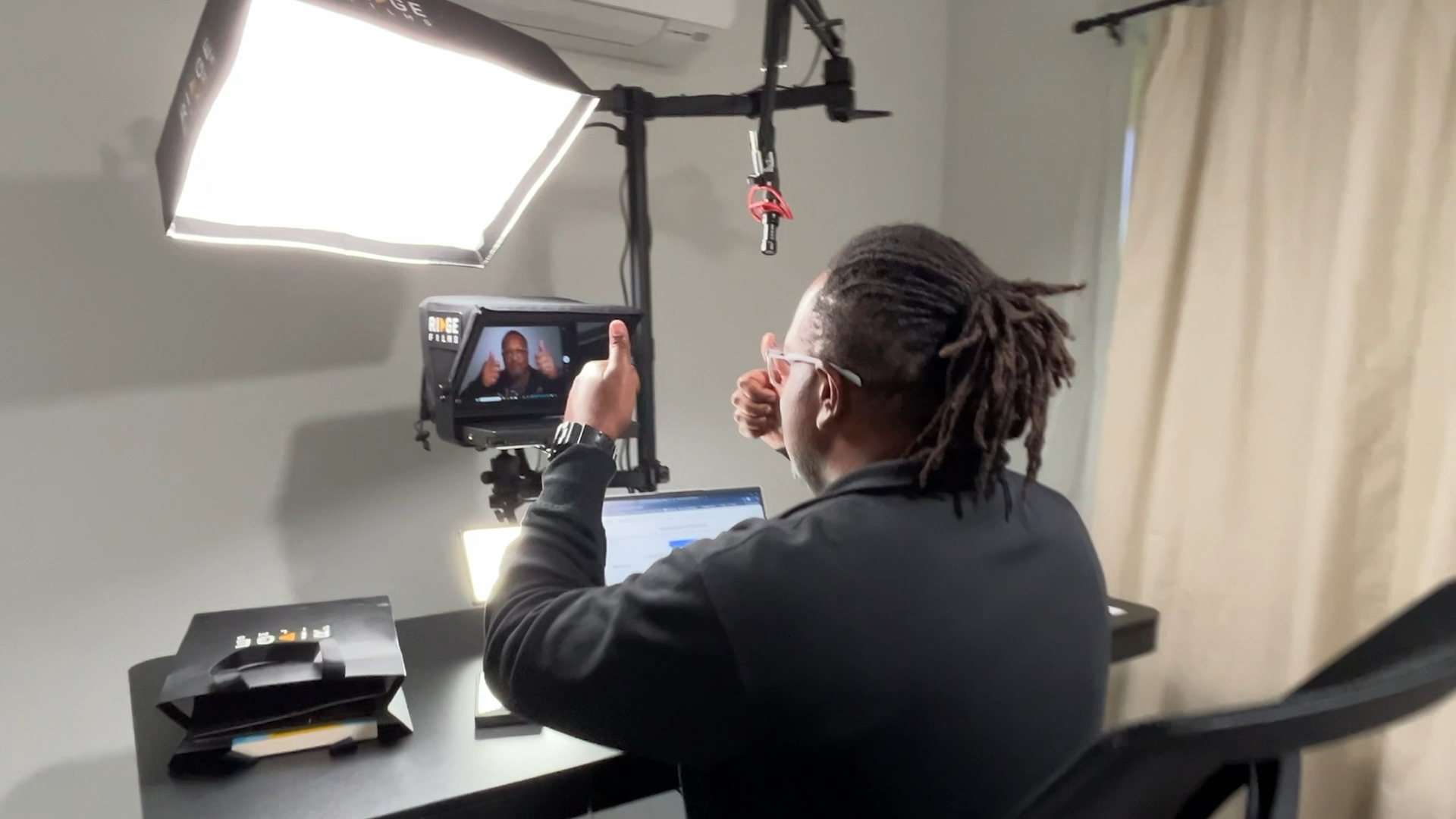 A Ridge client gesturing mid-take at his teleprompter under a softbox light