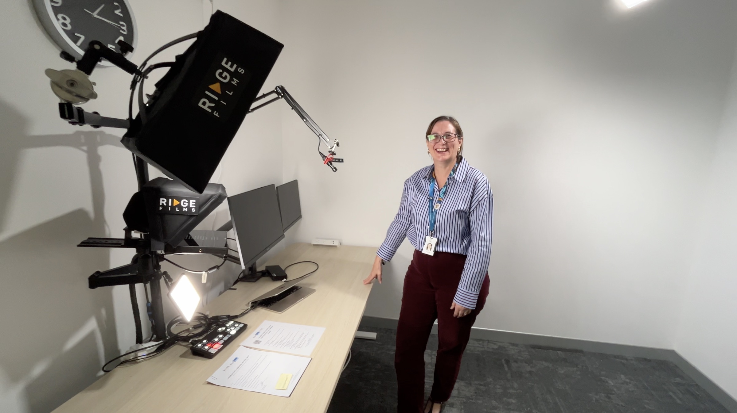 A Desktop Studio client smiling beside her new Ridge desk studio in a white office