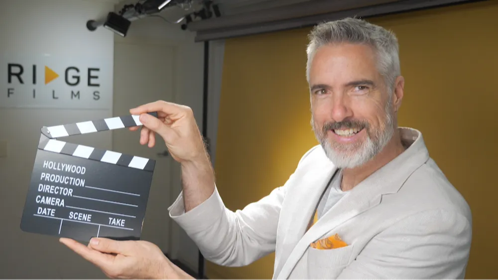 Chris Schwager holding a clapperboard in the Desktop Studio
