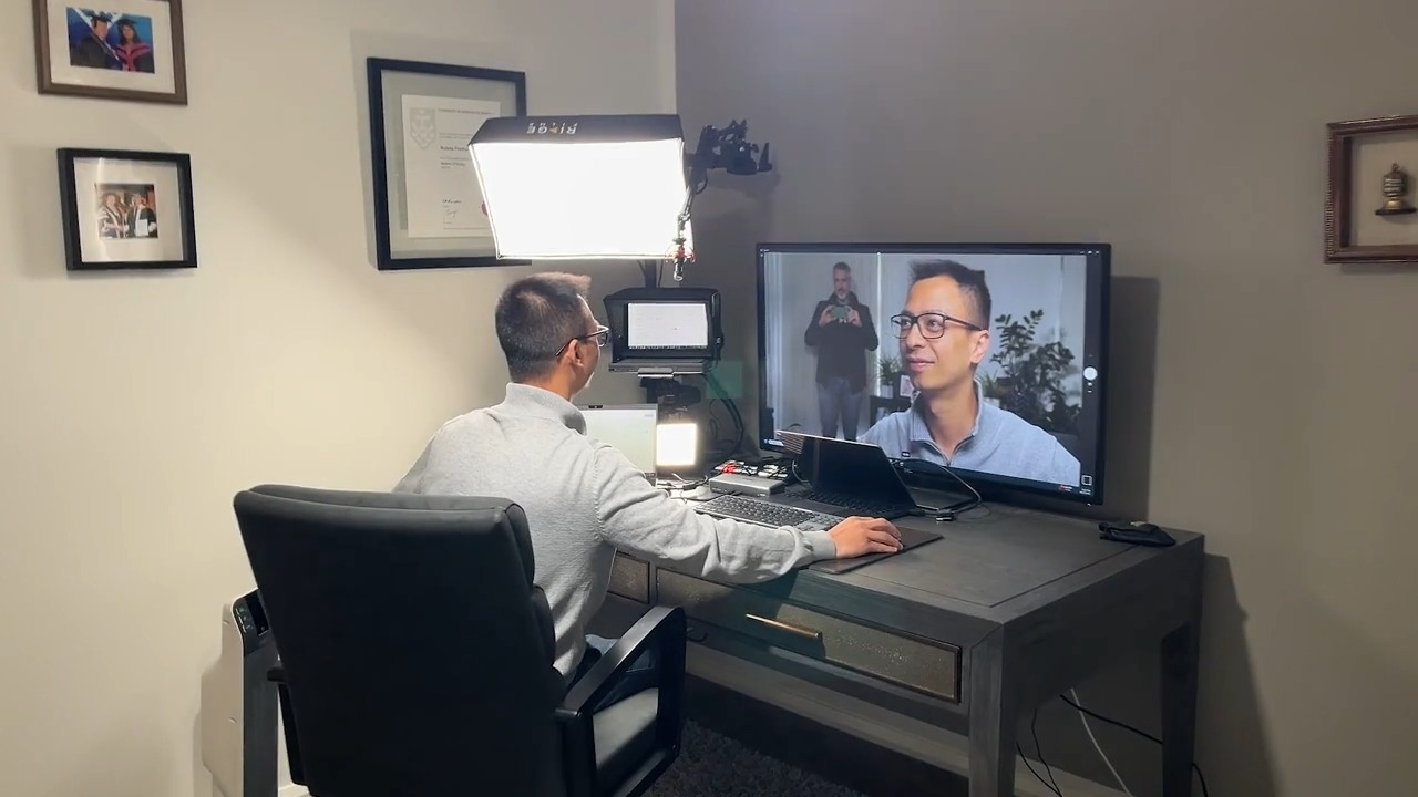 A Ridge client on a video call at his desk, with a softbox, teleprompter and a large monitor