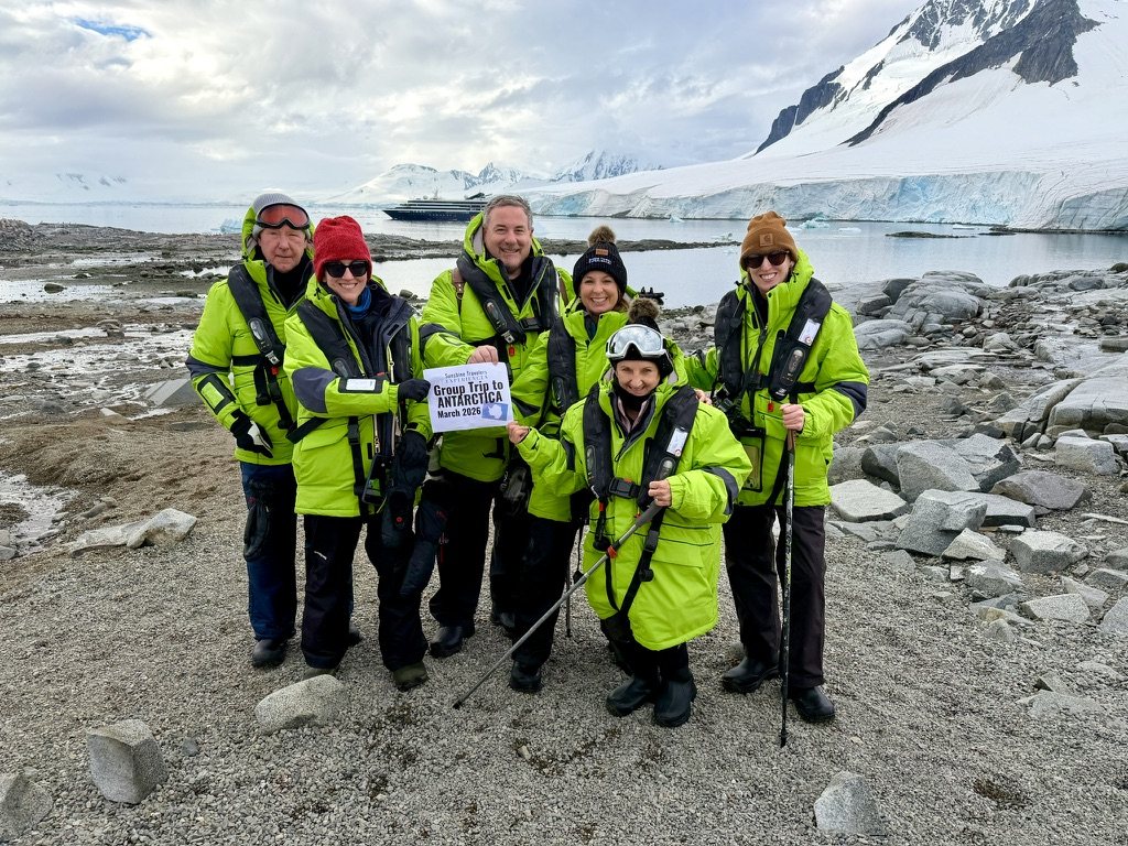 Sunshine Travelers Experiences group holding a sign on our first group trip to Antarctica, March 2026