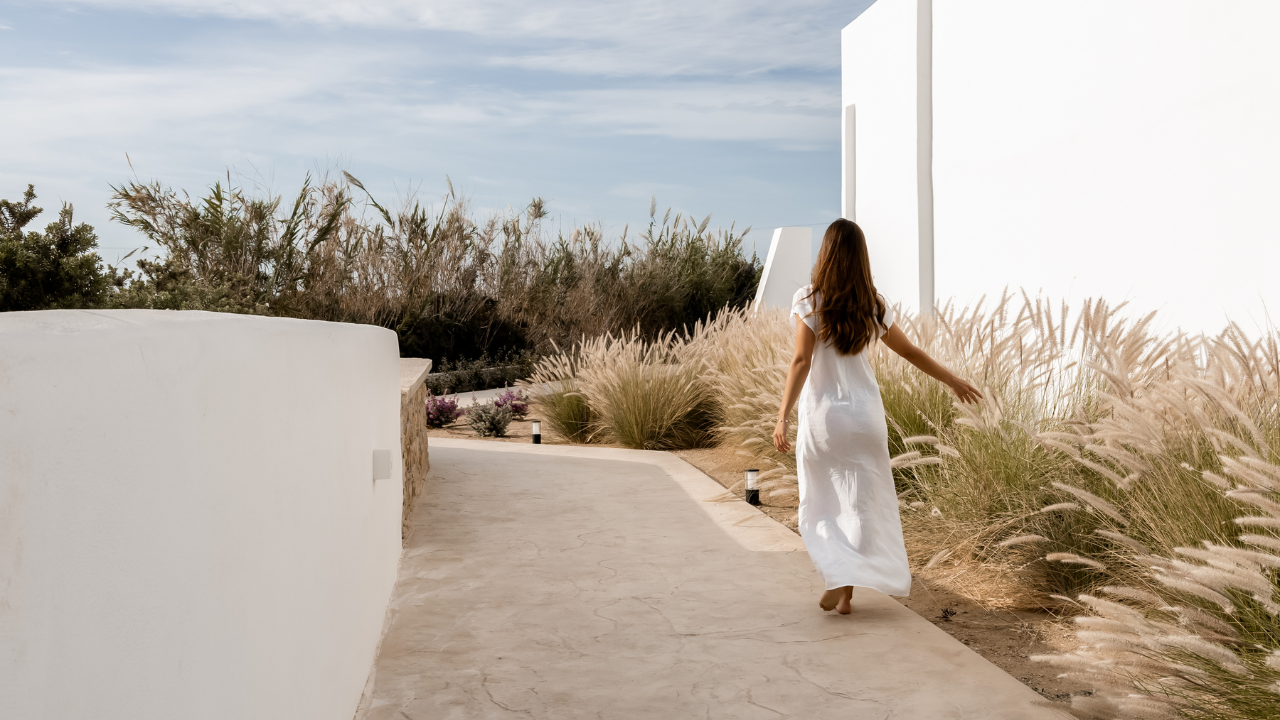 Woman in white dress walking along a sun-bleached Mediterranean pathway surrounded by wild grasses — The Rest Test, The Female CEO