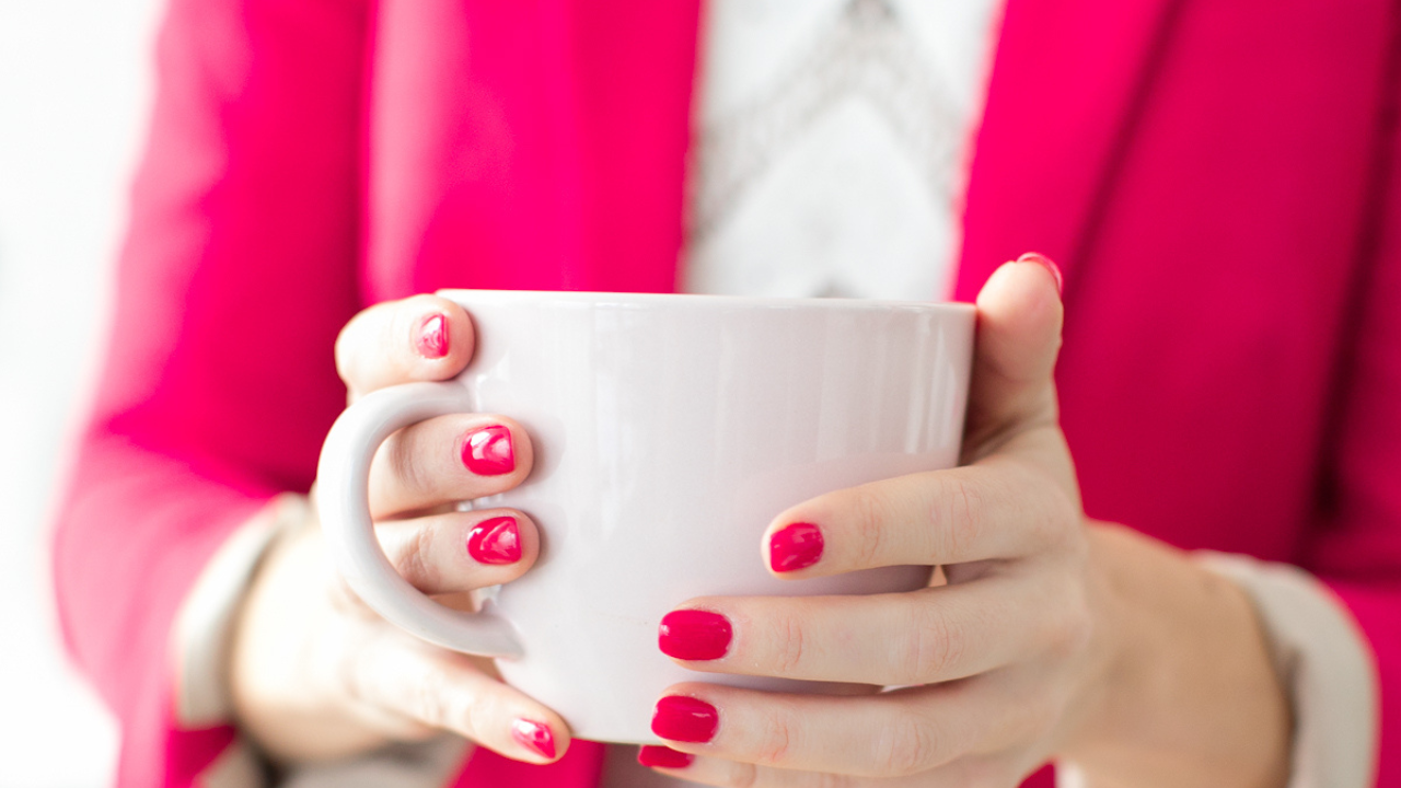 Woman in bright pink outfit holding a mug, symbolising confidence, colour psychology, and personal branding