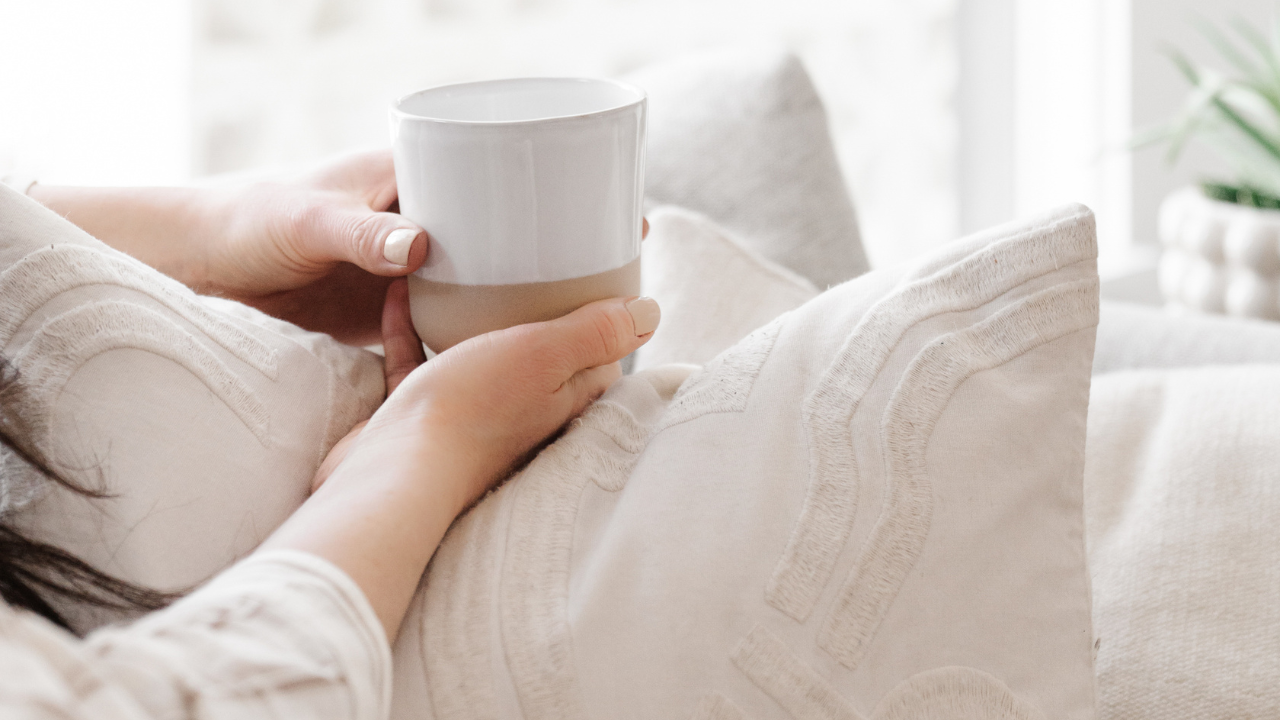 Person holding a warm drink at home, symbolising rest, mental clarity, and mindful leadership