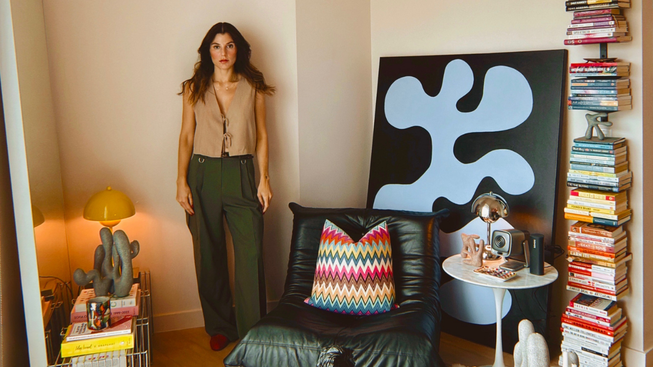 Shadia Sabagh in her Brickell home studio, beside a leather sofa, towers of books and a blue abstract canvas.