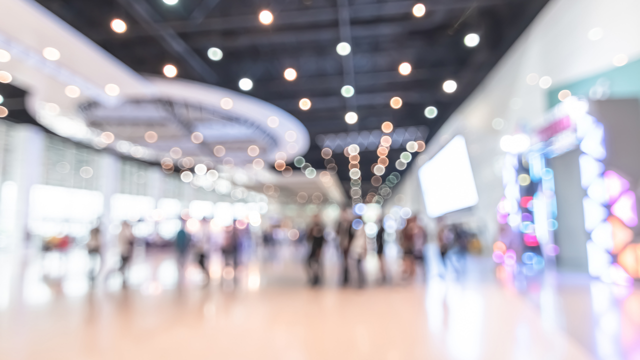 Busy trade show event space with exhibition booths and attendees networking in a modern conference hall