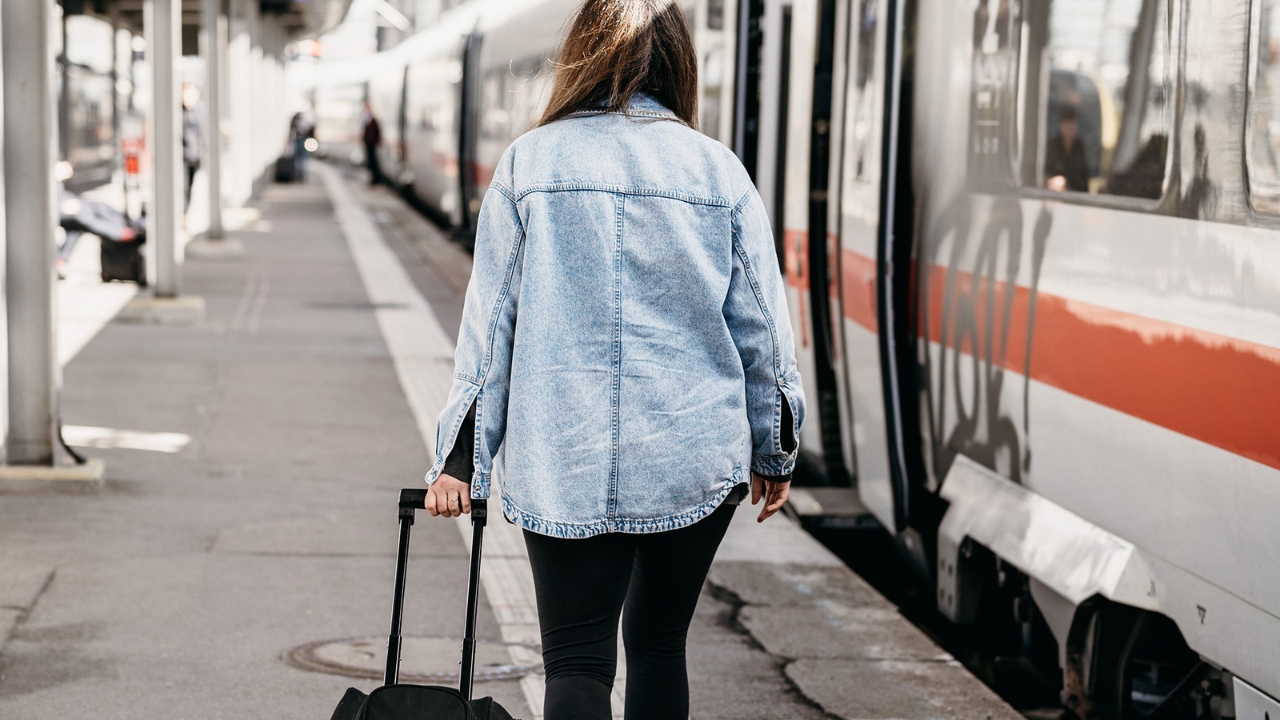 Female entrepreneur boarding a train with luggage, representing the concept of trainstorming and creative thinking away from the office