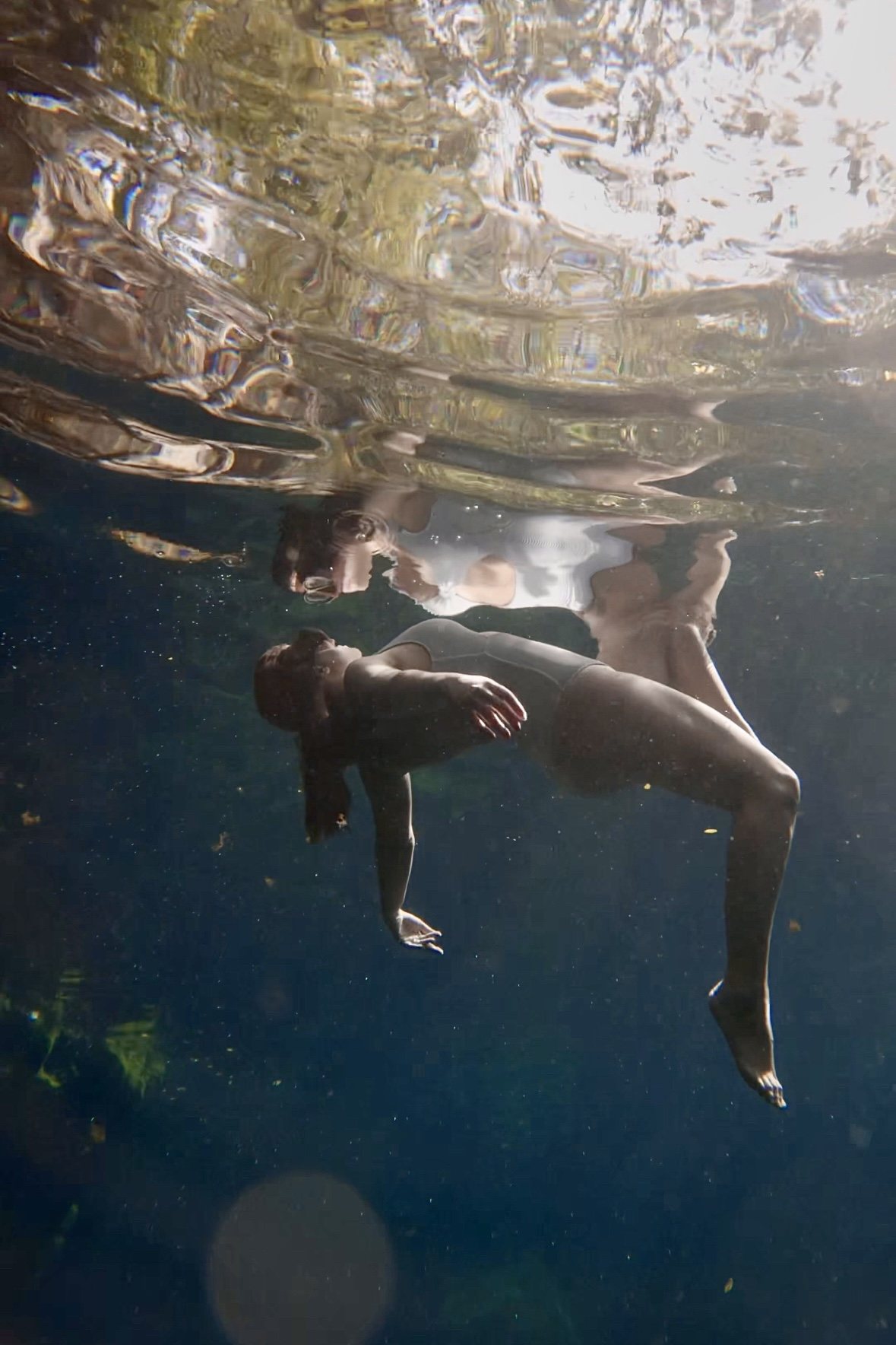 Woman floating beneath her reflection in a cenote