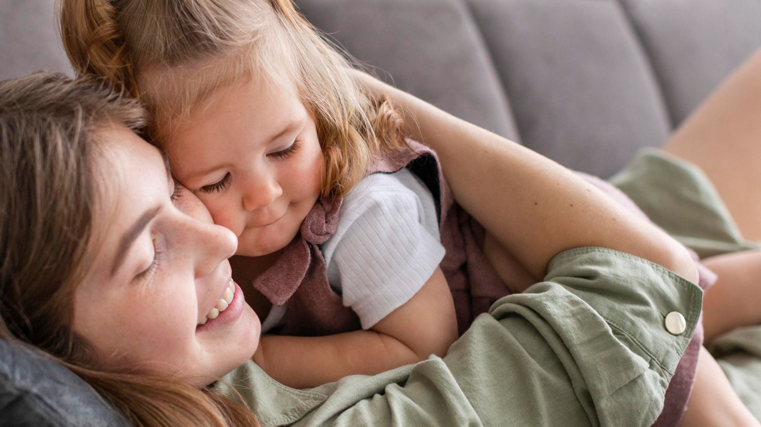 Mother and child cuddling on couch, showing connection in everyday motherhood
