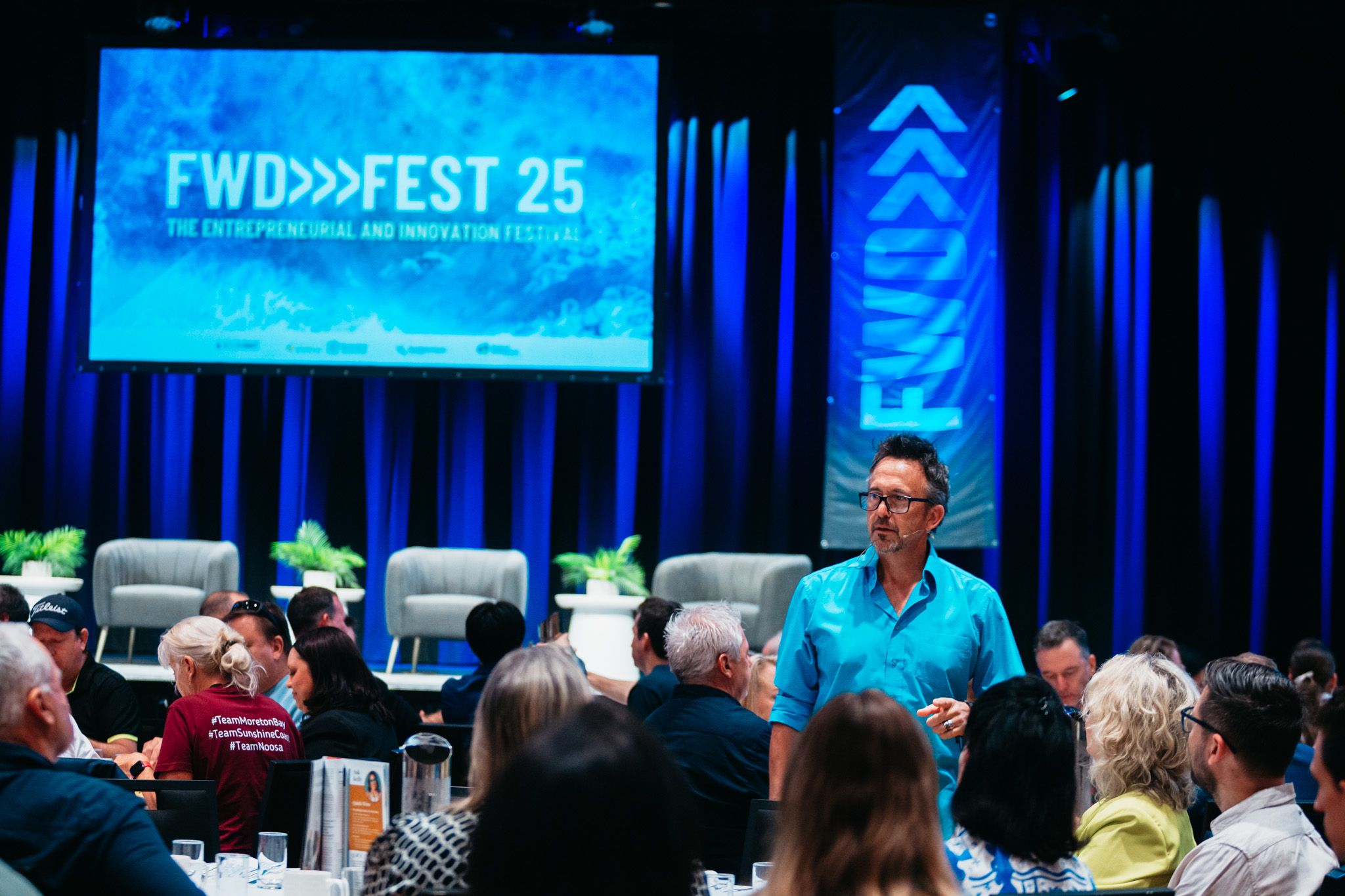 Dave Clare speaking among delegates at FWD Fest, with the conference stage behind him