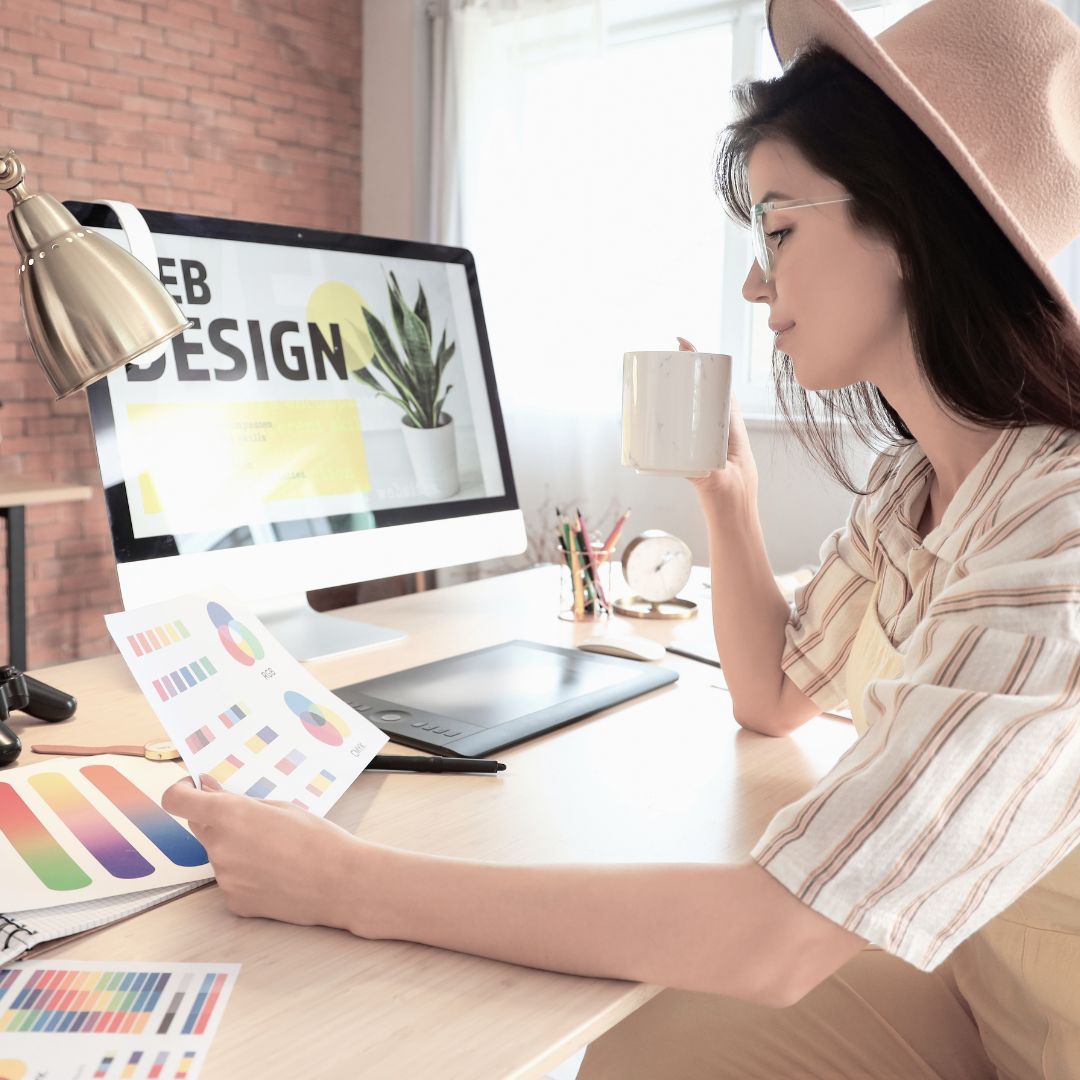 Designer comparing color palettes at her desk in front of a web design screen