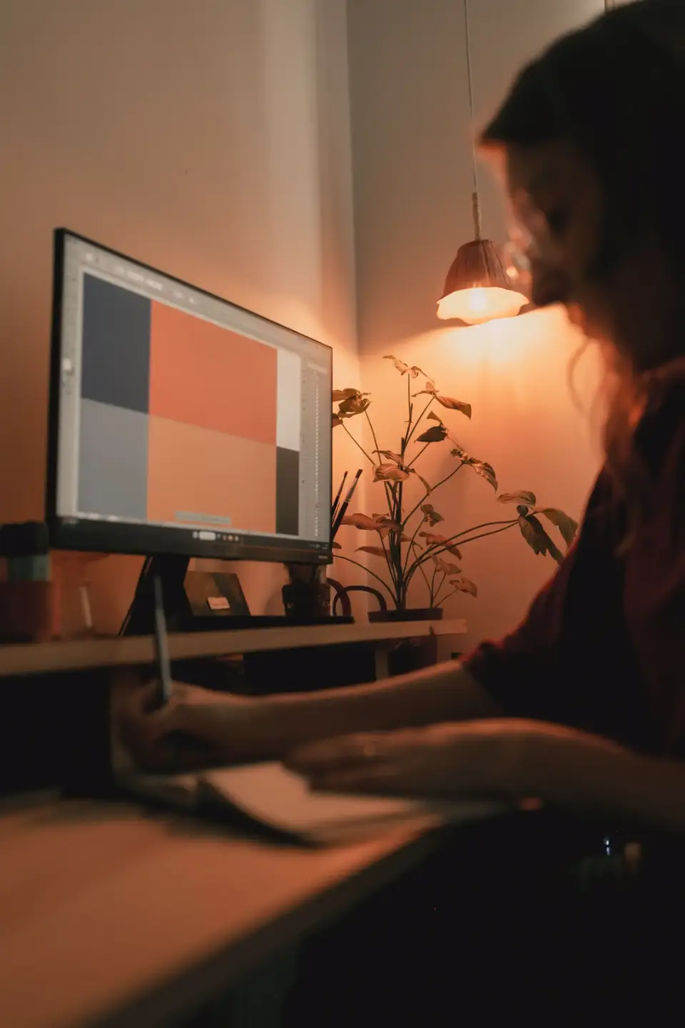 Woman in a black blazer opening her laptop at a sunlit desk